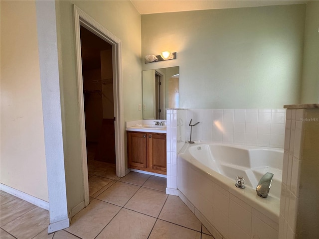 full bath featuring a garden tub, a spacious closet, vanity, baseboards, and tile patterned floors