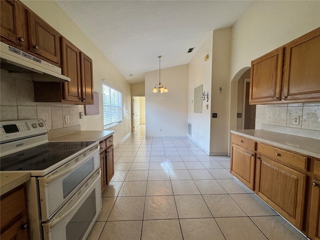 kitchen with lofted ceiling, light tile patterned flooring, double oven range, under cabinet range hood, and baseboards