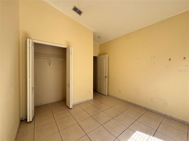 unfurnished bedroom with light tile patterned floors, a closet, visible vents, and baseboards