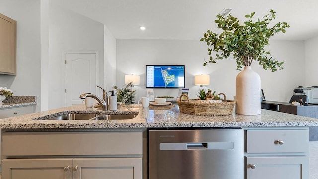 kitchen with gray cabinets, a sink, an island with sink, and light stone countertops