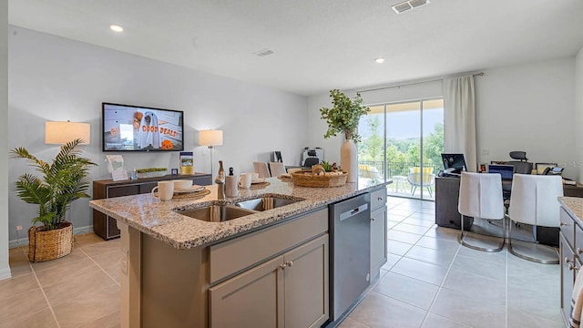 kitchen with visible vents, an island with sink, light stone counters, gray cabinetry, and stainless steel dishwasher