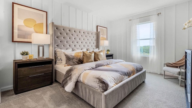 bedroom featuring light carpet and a decorative wall