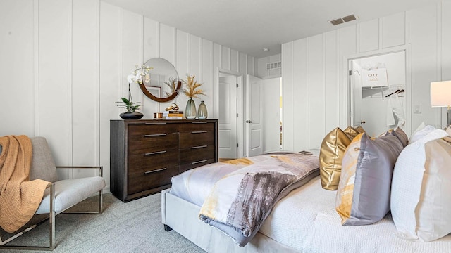 bedroom with a spacious closet, visible vents, and light colored carpet