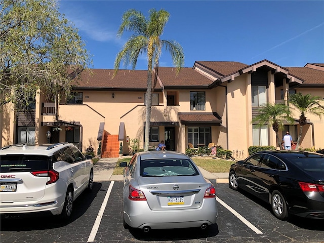 multi unit property with stairs, uncovered parking, and stucco siding