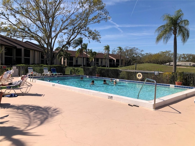 community pool with a residential view, a patio area, and fence