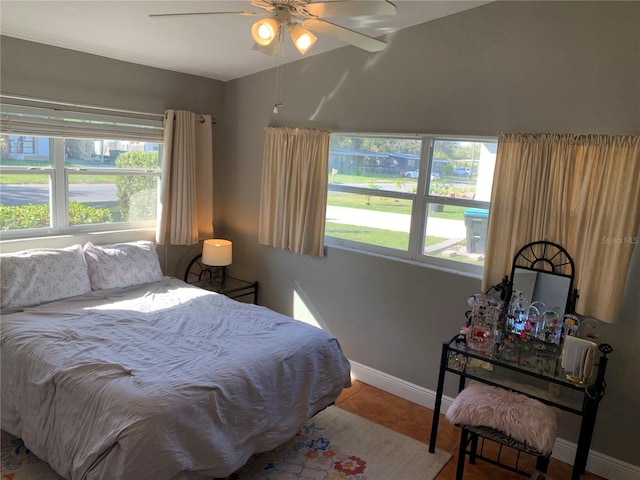 tiled bedroom with vaulted ceiling, a ceiling fan, and baseboards