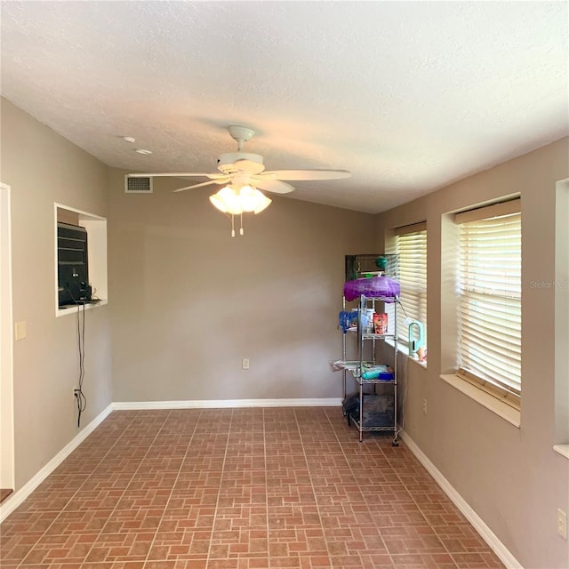 217 Wilmer Ave, Orlando, FL 32811 - unfurnished room featuring a textured ceiling, brick floor, baseboards, visible vents, and ceiling fan