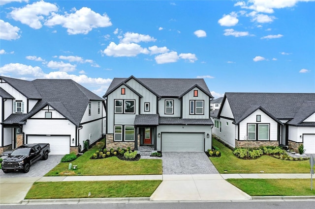 modern farmhouse featuring decorative driveway, an attached garage, board and batten siding, stone siding, and a front lawn