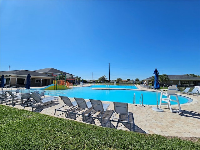 community pool featuring playground community, a water slide, and a patio