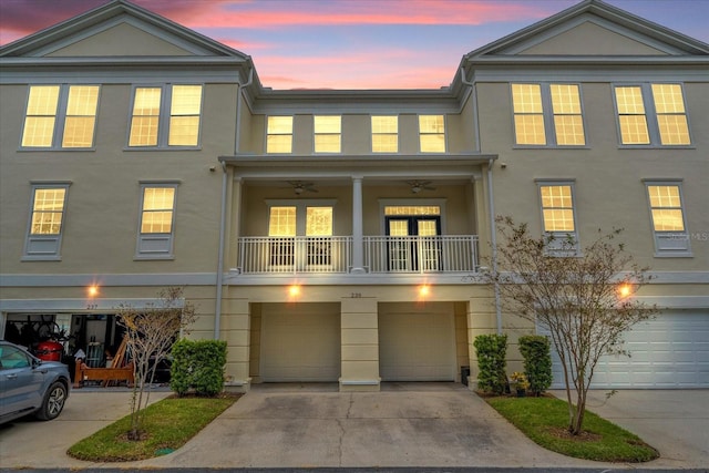 view of property featuring driveway, an attached garage, a balcony, and stucco siding