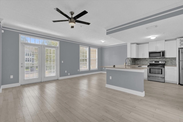 kitchen with light wood-style flooring, decorative backsplash, stainless steel appliances, and light countertops