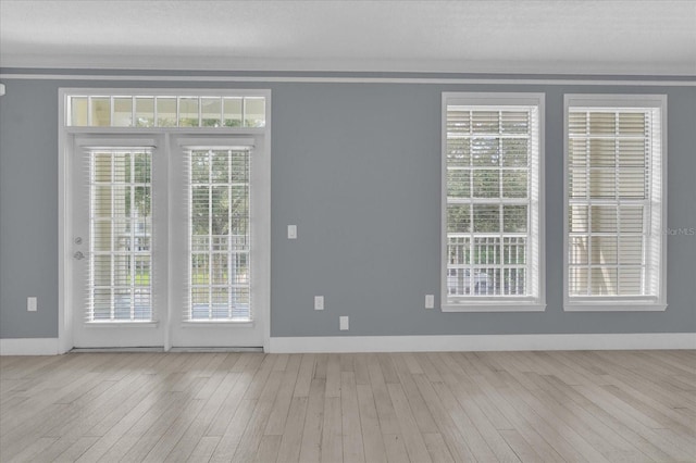 spare room with hardwood / wood-style flooring, a wealth of natural light, and baseboards