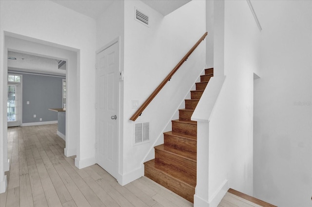 stairs featuring wood finished floors, visible vents, and baseboards