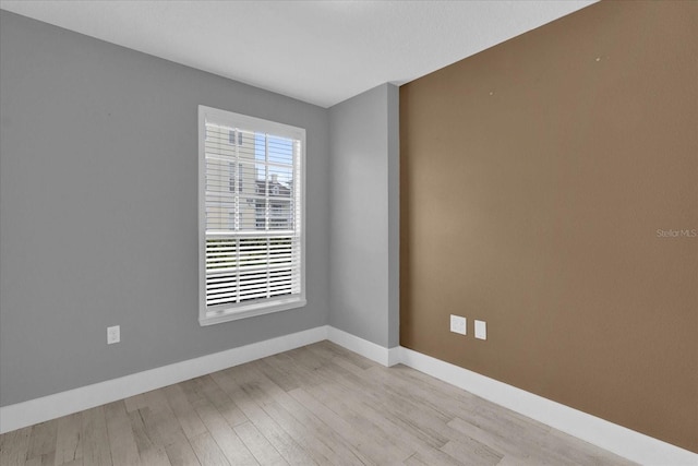 empty room featuring light wood finished floors and baseboards