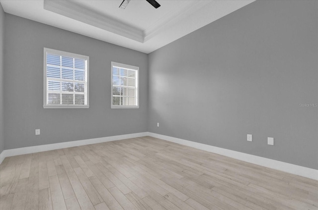 spare room featuring a ceiling fan, a tray ceiling, baseboards, and wood finished floors