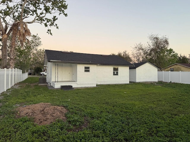 rear view of property featuring entry steps, a fenced backyard, a yard, and central AC