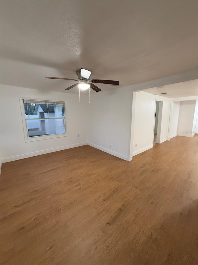 spare room with baseboards, a ceiling fan, and wood finished floors