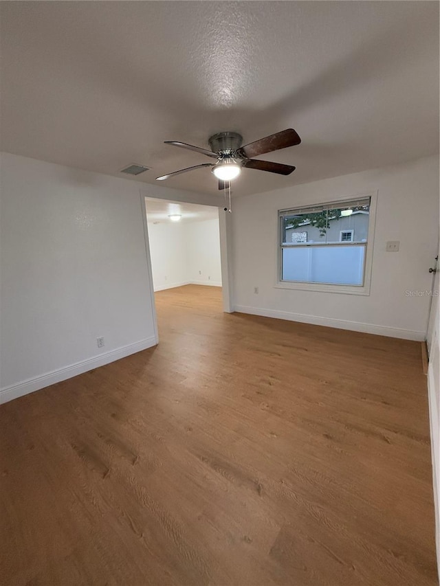 empty room with ceiling fan, baseboards, visible vents, and light wood-style floors