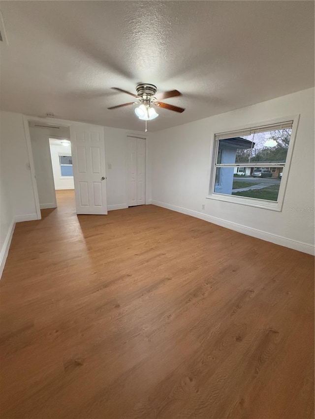 unfurnished room with light wood-style floors, a textured ceiling, and baseboards