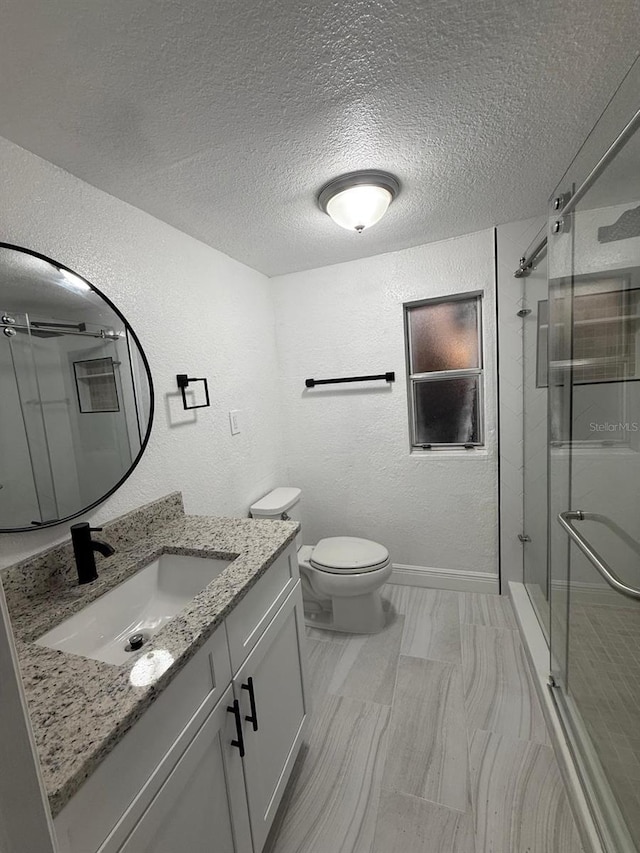 full bath with a textured wall, a stall shower, and vanity