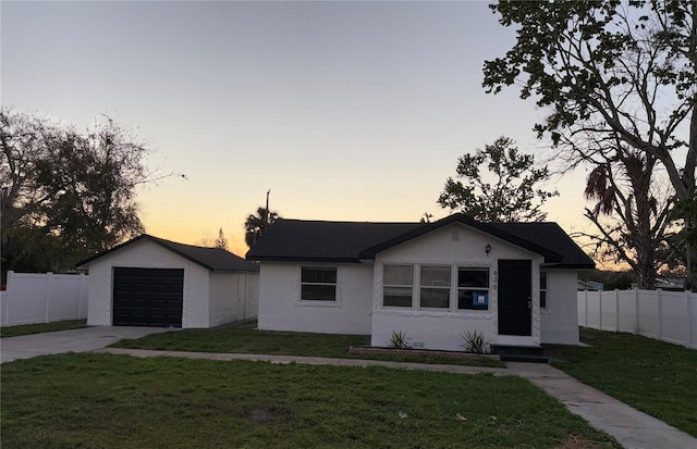 view of front of property featuring concrete driveway, fence, an outdoor structure, a front yard, and stucco siding