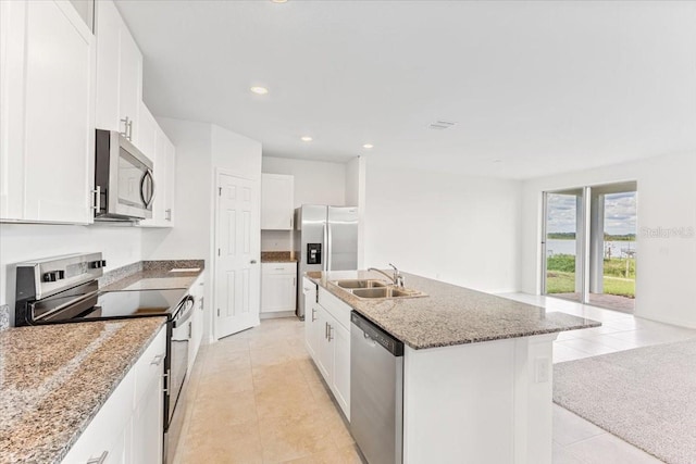 kitchen with a kitchen island with sink, a sink, white cabinets, appliances with stainless steel finishes, and light stone countertops