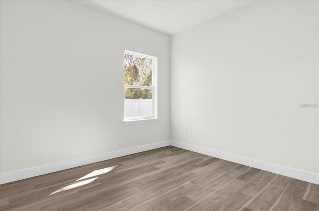 spare room featuring baseboards and wood finished floors