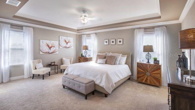 bedroom featuring a tray ceiling, multiple windows, and visible vents