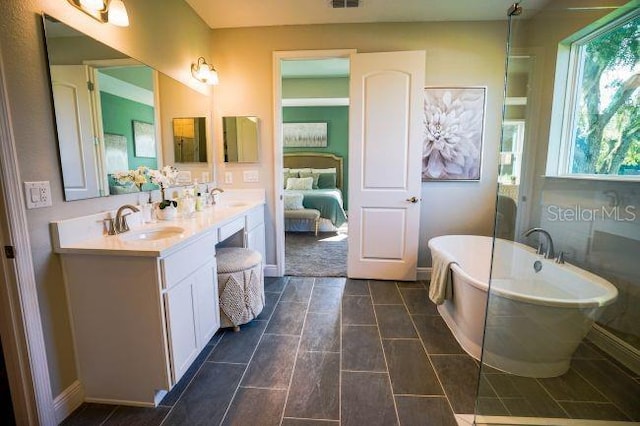 ensuite bathroom featuring a freestanding tub, visible vents, a sink, and double vanity