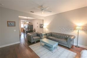 living area featuring ceiling fan, baseboards, and wood finished floors