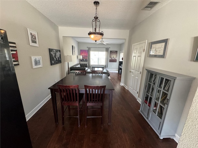 dining room with a textured ceiling, dark wood-style flooring, visible vents, and baseboards