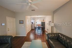 living room featuring ceiling fan, wood finished floors, visible vents, and baseboards