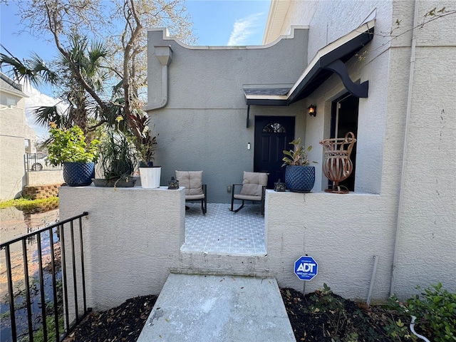 view of exterior entry featuring fence and stucco siding