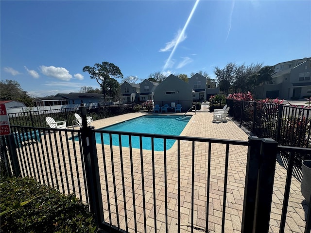 community pool with a patio, fence, and a residential view