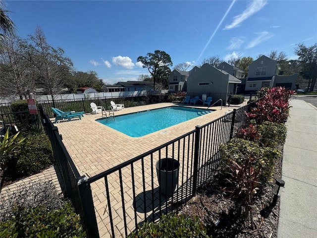 community pool featuring a residential view, a patio area, and fence