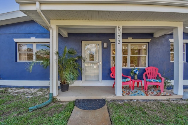 doorway to property featuring a porch and stucco siding