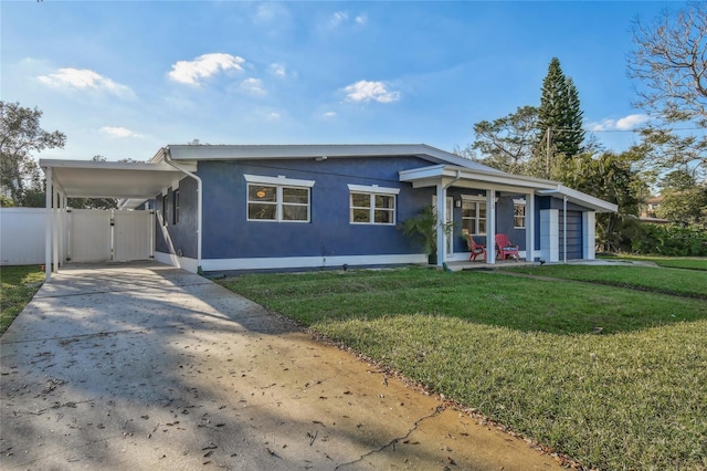 view of front of home with stucco siding, concrete driveway, fence, an attached carport, and a front lawn