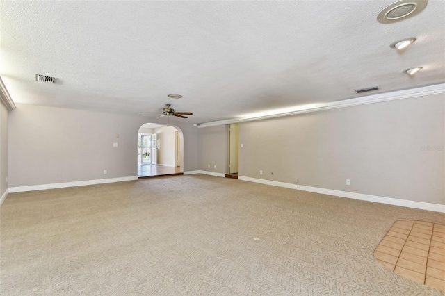 unfurnished room with arched walkways, visible vents, a ceiling fan, light carpet, and a textured ceiling