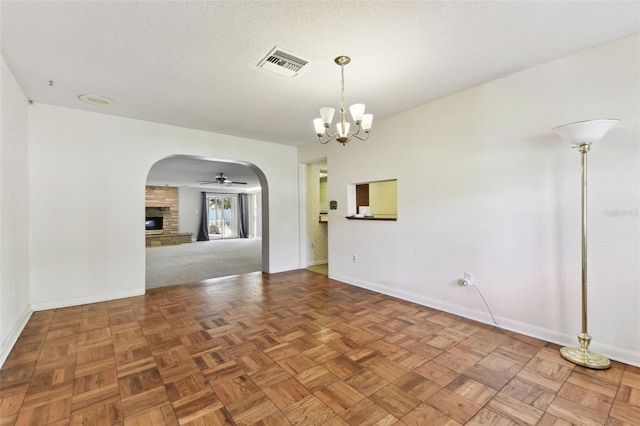 unfurnished room featuring arched walkways, a fireplace, visible vents, a textured ceiling, and baseboards