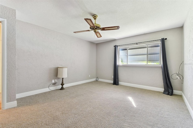 carpeted spare room featuring baseboards, a ceiling fan, a textured ceiling, and a textured wall