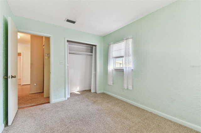 unfurnished bedroom featuring a closet, carpet, visible vents, and baseboards