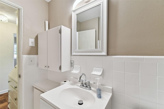 bathroom with a wainscoted wall, tile walls, and vanity