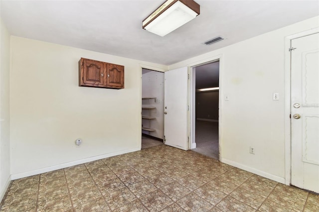 unfurnished bedroom with baseboards, visible vents, a spacious closet, and light floors