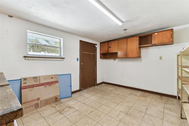 kitchen featuring baseboards, brown cabinets, and light countertops