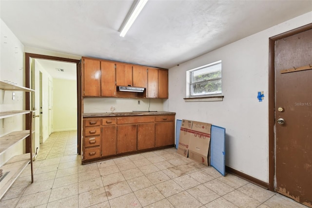 kitchen featuring baseboards, visible vents, and brown cabinets