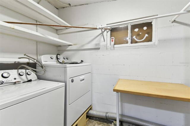 clothes washing area with concrete block wall, laundry area, and washing machine and dryer