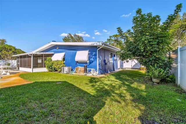 back of property with central air condition unit, a lawn, a sunroom, a patio area, and a fenced backyard