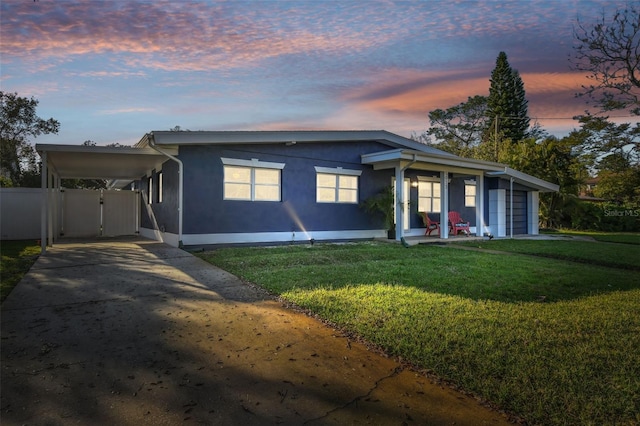 view of front of home with a yard, concrete driveway, a carport, and fence