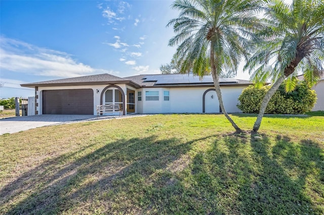 ranch-style home featuring driveway, an attached garage, roof mounted solar panels, a front lawn, and stucco siding