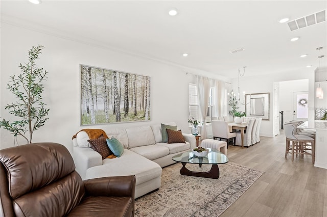 living area with ornamental molding, light wood-type flooring, visible vents, and recessed lighting